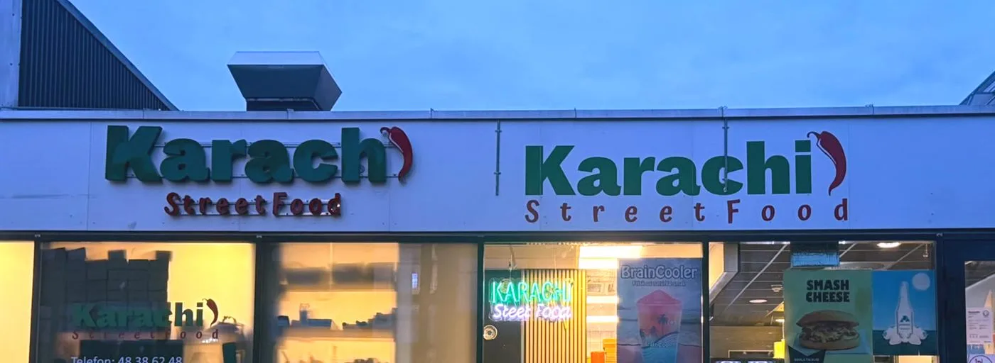 Fasaden til Karachi Streetfood med lysskilt i skumringen