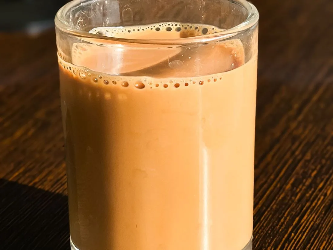 Tykk chai i glass på mørkt trebord